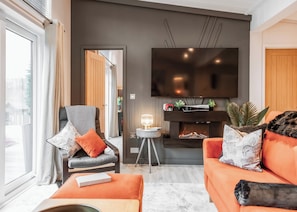 Un salon moderne avec un canapé, un fauteuil et un téléviseur à écran plat fixé au mur.