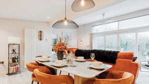Ein stilvoller Essbereich mit einem Marmortisch, orangefarbenen Stühlen und einem schwarzen Sofa.
