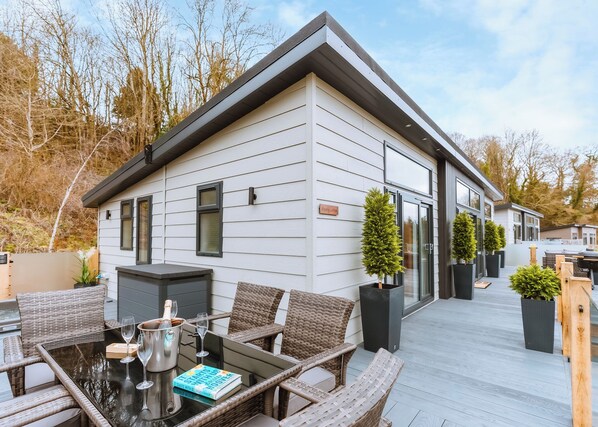 A modern house with a deck, wicker furniture, and a book titled 'Starts with Us Together.'