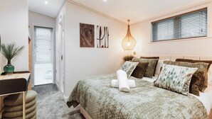Ein Schlafzimmer mit Bett, Nachttisch, Lampe und einem Fenster mit Jalousien.