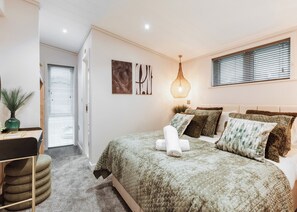 Une chambre à coucher avec un lit, une table de chevet, une lampe et une fenêtre avec des stores.