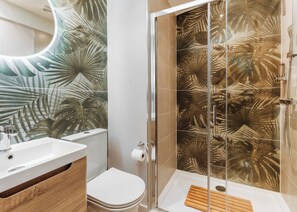 Une salle de bain avec douche, toilettes et lavabo.