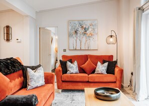 A living room with a sofa set, a painting, a floor lamp, and a coffee table.