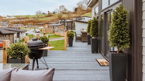 Eine Terrasse mit Grill, Topfpflanzen und Blick auf eine Wohngegend.