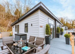 Une maison moderne dotée d’une terrasse, de meubles en osier et d’un livre intitulé « Tout commence avec nous, ensemble ».