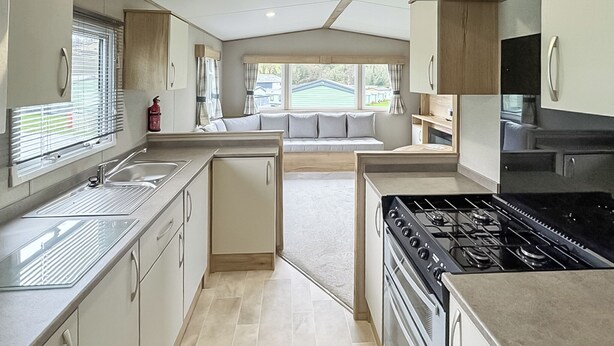 A modern kitchen with a central island, a stove, and a sink. - Luxury caravan with one double and one twin room. (Llanrhystud, Cardiganshire)