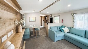 A modern living room with a sofa, a dining table set, and a kitchen area in the background. - 1 bedroom accommodation in Thirsk (Thirsk)