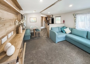 Ein modernes Wohnzimmer mit einer Couch, einem Esstisch und einer Küche im Hintergrund.