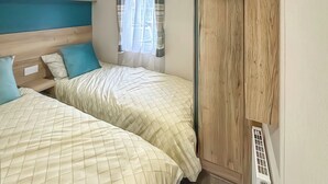 A bedroom with two beds, a window with curtains, and a radiator. - 1 bedroom accommodation in Thirsk (Thirsk)