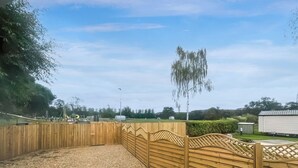 A fenced outdoor area with gravel ground, a wooden fence, and a small shed in the background. - 1 bedroom accommodation in Thirsk (Thirsk)