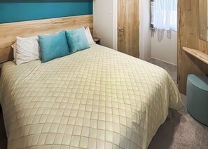 A bedroom with a bed, a wooden headboard, a wardrobe, and a small seating area. - 1 bedroom accommodation in Thirsk (Thirsk)