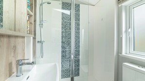 A modern bathroom with a glass-enclosed shower, a white sink, and a window. - Modern two-bedroom lodge, perfect for couples or families. (Presteigne)