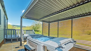 A hot tub with steps, a covered patio, and a view of the countryside. - Modern two-bedroom lodge, perfect for couples or families. (Presteigne)