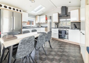 A modern kitchen with a dining area, featuring a built-in oven, a stove, and a skylight.
