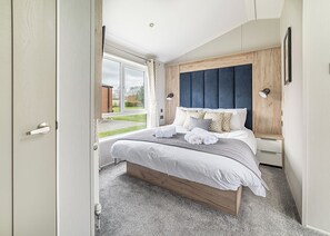 Une chambre à coucher avec un lit, des tables de chevet, une fenêtre et une porte.