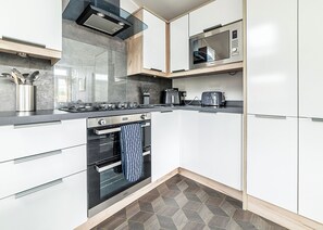 A modern kitchen with a gas stove, oven, microwave, and a coffee maker. - Modern two-bedroom lodge, perfect for couples or families. (Presteigne)