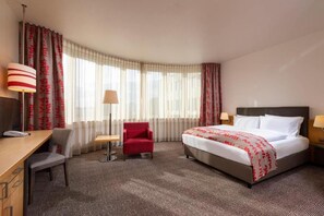 Hotellihuone, jossa on sänky, työpöytä, tuoli ja lamppu.