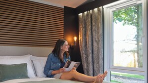 A person sitting on a bed in a room with a view of trees outside. - 1 bedroom accommodation in Arrochar (Arrochar)
