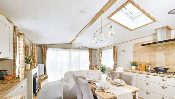 A compact RV interior with a dining area, kitchenette, and a skylight.