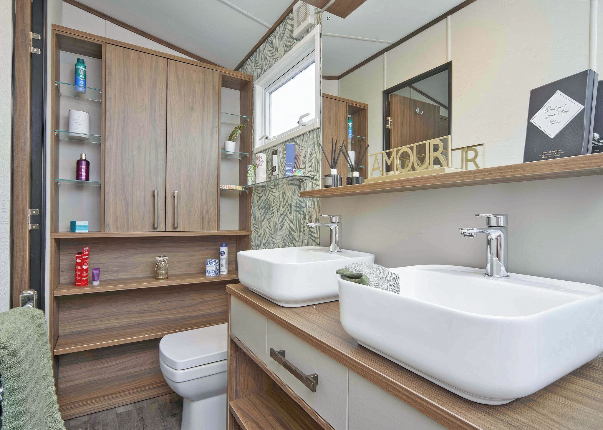 A modern bathroom with two sinks, a toilet, and a vanity with open shelves.