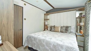 Et soveværelse med seng, et natbord, en garderobe og et spejl.
