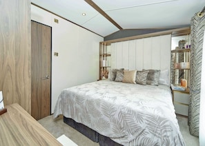 Un dormitorio con cama, mesita de noche, armario y espejo.