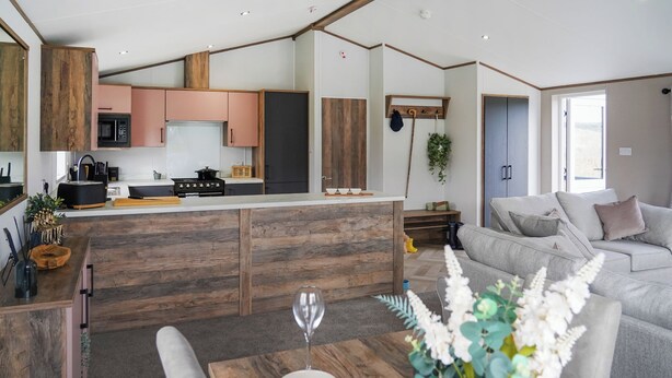 Une cuisine moderne avec des meubles en bois, un îlot central et un coin repas comprenant une table et des chaises.
