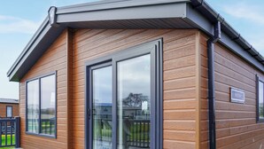 Un bâtiment moderne doté de grandes portes coulissantes en verre, d’une façade en bois et d’un toit en métal.