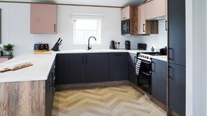 Une cuisine moderne dotée d’un îlot central, de meubles de rangement noirs, d’un four à micro-ondes, d’une machine à café et d’une cuisinière.