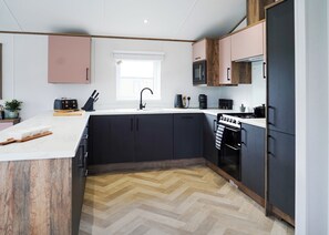 Una cocina moderna con una isla central, armarios negros, microondas, cafetera y estufa.