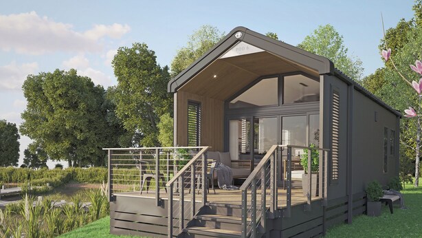 A modern, single-story cabin with a covered porch, a staircase, and a view of a pond.
