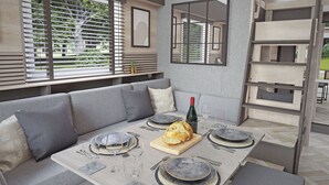 A modern dining area with a grey sofa, a wooden table set for four, and a large mirror on the wall.