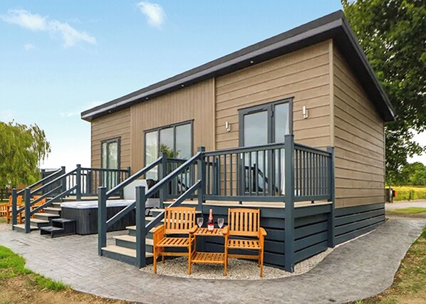Un bâtiment moderne à l’extérieur en bois, doté d’un balcon avec une balustrade et d’un escalier menant à l’entrée.