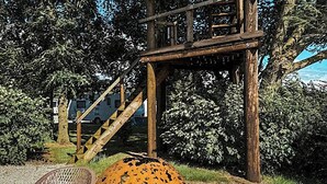 Una estructura de pérgola de madera, mobiliario exterior y una escalera que lleva a un nivel superior.