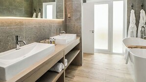 Un baño moderno con dos lavamanos, un espejo grande y una bañera.