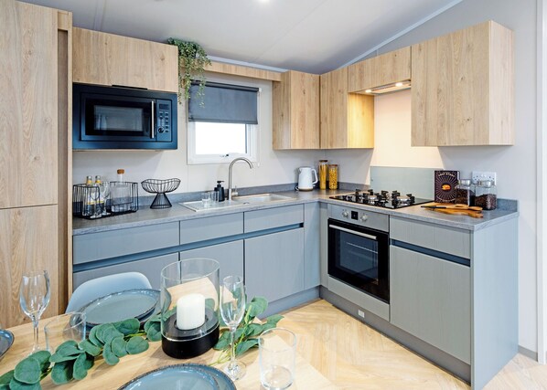 Una cocina moderna con microondas, estufa, lavabo y armarios de madera.
