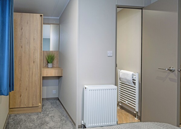 Une chambre avec une armoire, un radiateur, un porte-serviettes et une petite plante posée sur une étagère.