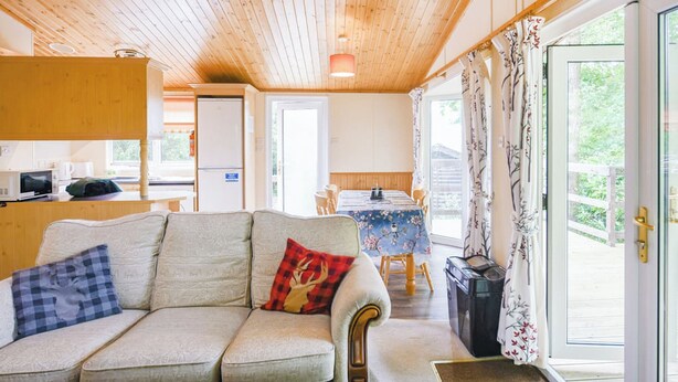 Un intérieur de chalet chaleureux avec un canapé, une table à manger et un coin cuisine.