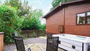 Un espace patio avec deux chaises, un jacuzzi et un chalet en bois.