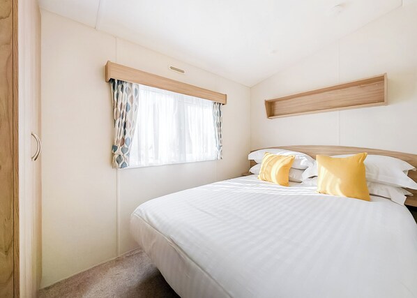 Une chambre à coucher avec un lit, des rideaux, une tête de lit et une étagère en bois.
