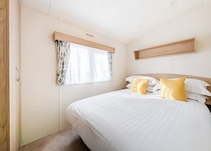 A bedroom with a bed, curtains, a headboard, and a wooden shelf.
