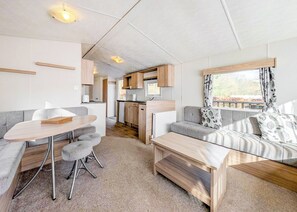Un intérieur de camping-car compact comprenant un coin cuisine, un canapé, une table à manger et un petit espace cuisine.