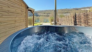 Un jacuzzi con estructura de madera y vistas a un paisaje natural.