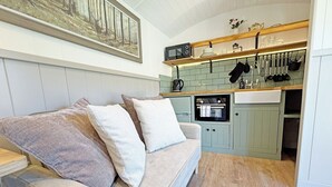 Un espacio de sala acogedor con un sofá, una cocina con microondas y un cuadro en la pared.