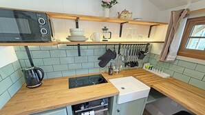 Una cocina compacta con microondas, estufa, lavaplatos y diferentes utensilios.