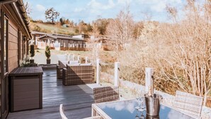 Eine Holzterrasse mit Korbmöbeln und einem Tisch, eine Champagnerflasche und Gläser.