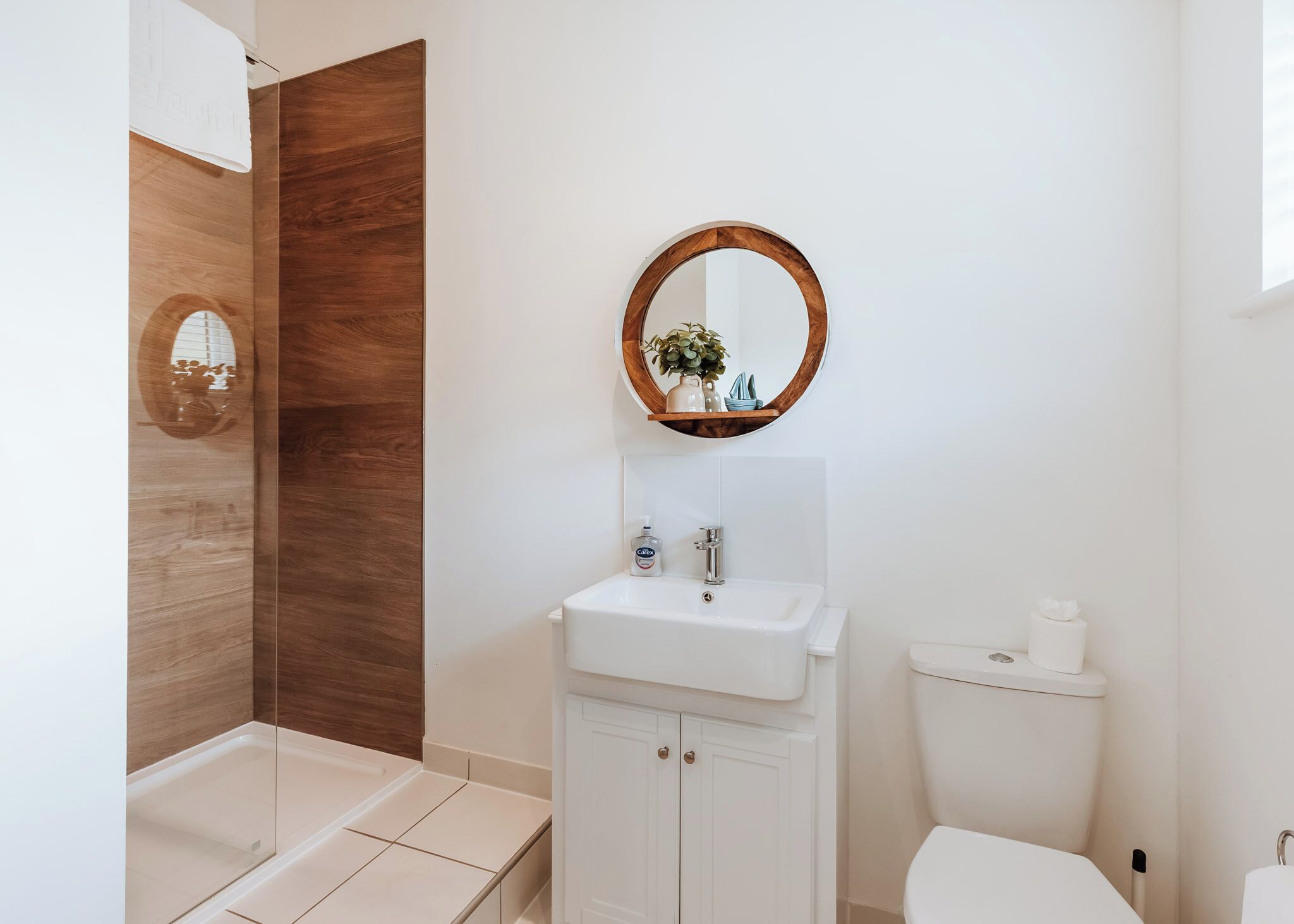 A modern bathroom with a shower, a sink with a mirror, and a toilet.