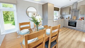 A modern kitchen with wooden cabinets, a built-in oven, and a dining area with a wooden table and chairs. - 2 bedroom accommodation in Market Bosworth, near Nuneaton (Market Bosworth, near Nuneaton)