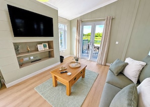 A living room with a flat-screen TV, wooden coffee table, and a sofa.