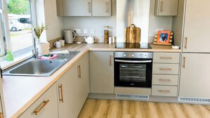 A compact kitchen with a built-in oven, a sink, and wooden cabinets. - 2 bedroom accommodation in Market Bosworth, near Nuneaton (Market Bosworth, near Nuneaton)